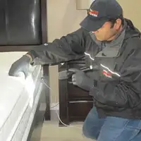 Bed bug inspection technician checking a mattress and bed frame for signs of infestation in South Bend, IN