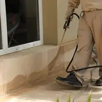 General pest control technician spraying exterior perimeter around a home in South Bend, IN