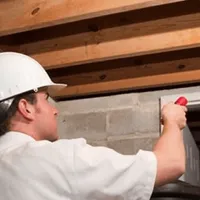Termite inspection technician checking a basement wall and framing for termite activity in South Bend, IN